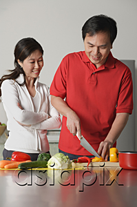 AsiaPix - Couple in kitchen, man cutting vegetables, woman watching him
