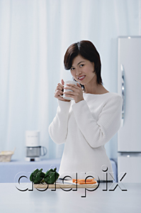 AsiaPix - Woman in kitchen, holding a mug, looking at camera