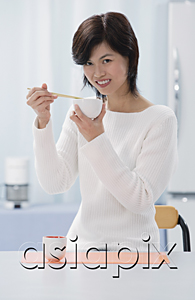 AsiaPix - Woman in kitchen, holding bowl and chopsticks