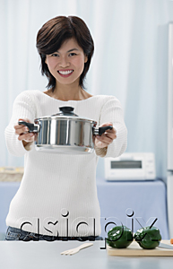 AsiaPix - Woman in kitchen, holding crocking pot towards camera