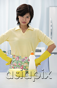 AsiaPix - Woman in kitchen with hands on hip, cleaning detergent and sponge on kitchen counter