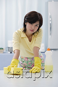 AsiaPix - Woman in kitchen wearing gloves, cleaning kitchen counter with sponge
