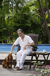AsiaPix - Mature man with his dog, sitting by swimming pool