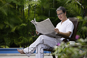 AsiaPix - Mature man sitting outdoors, reading newspaper