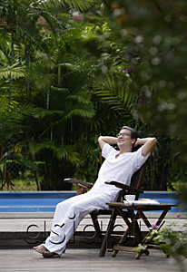 AsiaPix - Mature man sitting outdoors, hands behind head, looking up