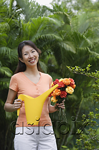 AsiaPix - Woman in garden, holding bouquet of flowers and watering can