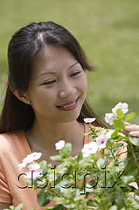AsiaPix - Woman outdoors, looking at flowering plants