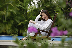 AsiaPix - Woman sitting outdoors, hand on head, smiling at camera