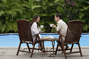 AsiaPix - Couple sitting by swimming pool, have drinks, looking at each other