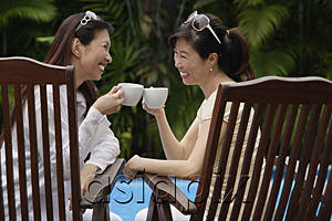 AsiaPix - Two women sitting outdoors, toasting with cups