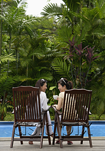 AsiaPix - Two women sitting and talking by swimming pool