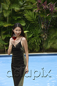 AsiaPix - Woman standing and holding a glass of wine, swimming pool in the background