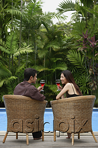 AsiaPix - Couple sitting by swimming pool, drinking wine