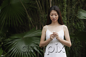 AsiaPix - Woman in white dress, outdoors, looking at flower in her hand