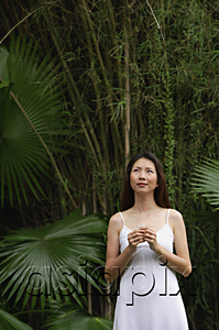 AsiaPix - Woman standing outdoors, looking up, hands clasped