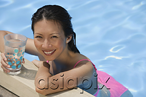 AsiaPix - Woman leaning on edge of swimming pool, holding a drink, smiling at camera