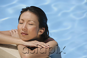 AsiaPix - Woman leaning at the edge of swimming pool, arms crossed, eyes closed