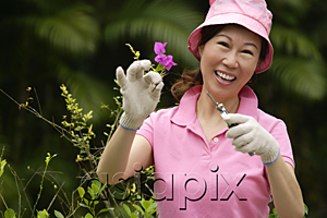AsiaPix - Woman pruning plants, smiling at camera