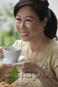 AsiaPix - Woman with cup and saucer, having a drink, smiling