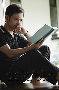 AsiaPix - Man reading a book, serious expression