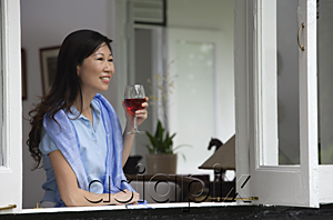 AsiaPix - Woman at home, looking out of the window, holding wine glass