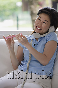 AsiaPix - Woman filing her nails and talking on telephone