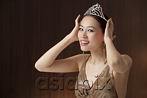 AsiaPix - woman wearing crown, hands on crown on head, smiling at camera