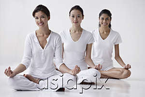 AsiaPix - three women of mixed race sitting in yoga posture OM, meditating, looking at camera, smiling