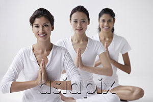 AsiaPix - three women of mixed race sitting with legs crossed, arms in namaste, smiling at camera