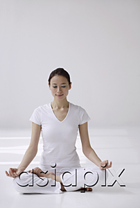 AsiaPix - Woman sitting cross legged on floor, meditating, eyes closed