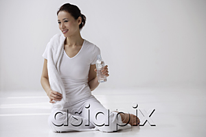 AsiaPix - Woman sitting on floor with towel and water bottle, relaxing