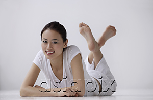 AsiaPix - Woman lying on stomach on floor, looking at camera, smiling