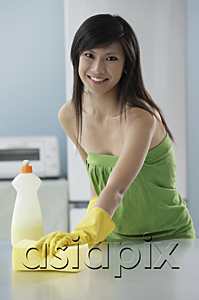 AsiaPix - woman in kitchen cleaning counter with sponge, smiling at camera