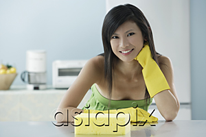 AsiaPix - woman in kitchen with sponge, wearing gloves, looking at camera, smiling