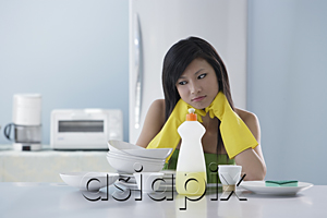 AsiaPix - woman in kitchen, looking at pile of dishes, thinking