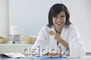 AsiaPix - woman in kitchen wearing bathrobe, holding cooking, smiling at camera, reading magazine