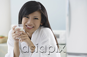 AsiaPix - woman in kitchen, holding glass of milk, smiling at camera