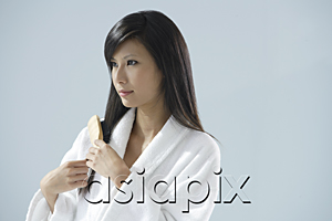 AsiaPix - woman wearing bathrobe, brushing hair and looking away from camera