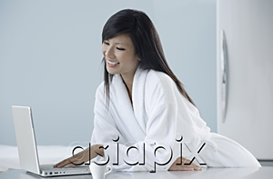 AsiaPix - woman wearing bathrobe in kitchen, looking at computer, laptop, smiling