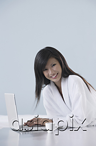 AsiaPix - woman wearing bathrobe, smiling and working on laptop computer, smiling at camera