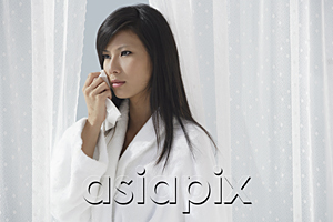 AsiaPix - woman looking sad and wiping tears from her eyes, thinking