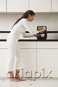 AsiaPix - Woman in kitchen making coffee, cappuccino