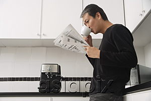 AsiaPix - Man in kitchen, drinking coffee and reading paper