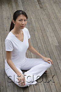 AsiaPix - woman sitting crossed legged on porch, relaxing, looking at camera.