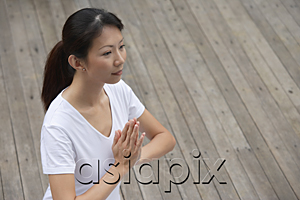 AsiaPix - Woman on porch in yoga posture, hands in namaste,