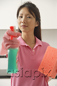 AsiaPix - Woman cleaning with cleaning spray and sponge, spraying at camera