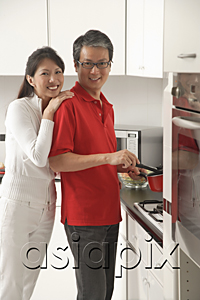 AsiaPix - Man and woman in kitchen cooking, looking at camera, smiling