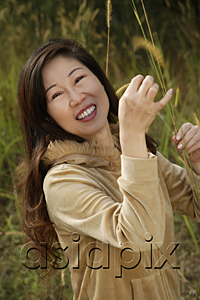 AsiaPix - Woman outside standing in tall grass, smiling at camera