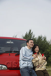 AsiaPix - man and woman leaning against front of red van, holding drinks, nature, camping, outdoors