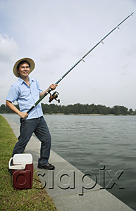 AsiaPix - Man fishing with fishing pole, looking at camera, smiling